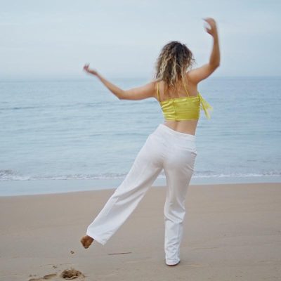 Home energetic girl dancing beach looking on beautiful ocean waves. w